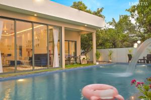 a house with a swimming pool with a pink ball in the water at EKOSTAY Luxe - Ivory Coast Villa in Alibaug +20 photos