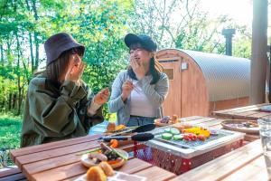 zwei Frauen sitzen an einem Picknicktisch mit Essen in der Unterkunft 日本文化に触れる日光リゾート貸切Villa 最大10名 プライベートサウナ 雨でもBBQ にぎわいOK 完全プライベート空間 in Ochikawa