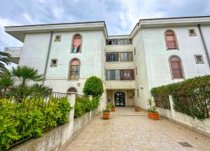 ein großes weißes Gebäude mit einem Gehweg davor in der Unterkunft La Cola Cola in Gravina in Puglia