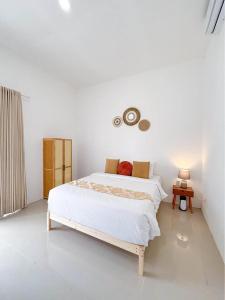 a white bedroom with a bed and a table at Yan Loft in Uluwatu