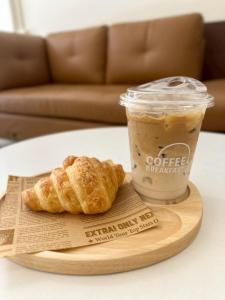una tazza di caffè e due croissant su un vassoio di legno di WanderFox a Chiang Mai