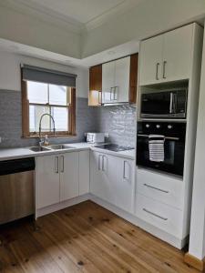 eine Küche mit weißen Schränken und einer Spüle und einer Mikrowelle in der Unterkunft Seabreaze cottage sleeps 6 in Portland + 4 Fotos