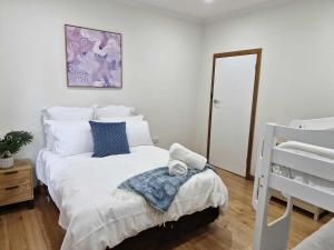 ein Schlafzimmer mit einem weißen Bett mit blauen Kissen in der Unterkunft Seabreaze cottage sleeps 6 in Portland