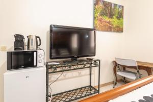 a flat screen tv sitting on a stand next to a refrigerator at Chambre calme, zen & lumineuse in Sevran