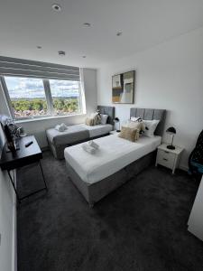 een witte kamer met 2 bedden en een bank bij Stylish 1BR with Comfy Vibes in Beckenham