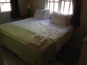 um quarto com uma cama com lençóis brancos e almofadas em Tony's Cottage em English Harbour Town
