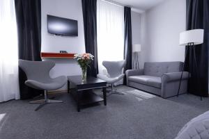 a living room with a couch and chairs and a tv at Hotel Felicia in Rīga