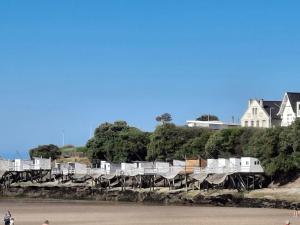 a row of chairs sitting on the side of a beach at Sous le Marronnier - Maison pour 4 avec jardin in Royan
