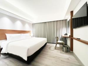 a bedroom with a large white bed and a desk at The Jogja Malioboro Hotel and Conference Center in Yogyakarta