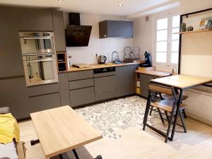 a kitchen with gray cabinets and a table and chairs at Jolie maison Foix in Foix