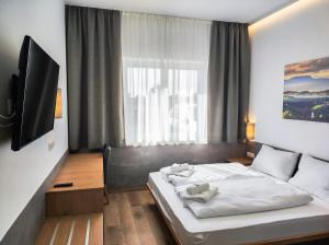 a bedroom with a bed and a large window at OEKOTEL Graz Airport in Kalsdorf bei Graz