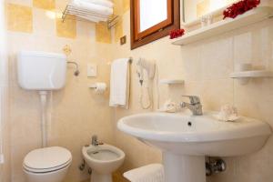 a bathroom with a sink and a toilet and a phone at Hotel Smeraldo in Lido di Jesolo +97 photos