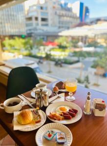 a table with breakfast foods and drinks on it at Triton Hotel Piraeus in Piraeus