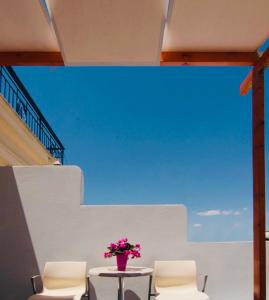 a table and chairs with a vase of flowers on it at Triton Hotel Piraeus in Piraeus