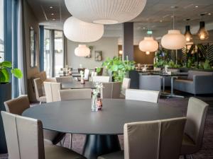 a dining room with tables and chairs and pendant lights at Quality Airport Hotel Værnes in Stjoerdal