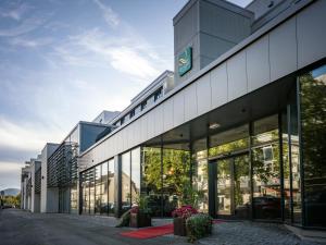 an office building with glass windows on a street at Quality Airport Hotel Værnes in Stjoerdal