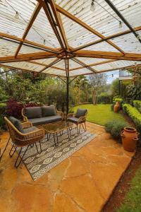 een patio met een bank en stoelen onder een parasol bij Nairobi Botanical Retreat - Container Home in Nairobi