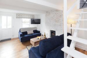 ein Wohnzimmer mit 2 blauen Sofas und einem Kamin in der Unterkunft Albert's Cottage, Dorset in Blandford Forum