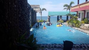 RedDoorz @ White Castle Beach Resort Iba Zambales في Iba: مجموعة من الناس في مسبح بالقرب من المحيط