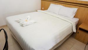 a white bed with a white flower on it at The Cabin Hotel Sumberan Baru in Ngabean