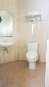 a bathroom with a white toilet and a sink at The Cabin Hotel Sumberan Baru in Ngabean