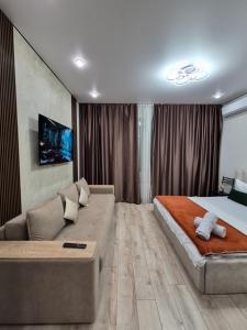 ein Schlafzimmer mit einem großen Bett und einer Couch in der Unterkunft Love & Happiness in Almaty
