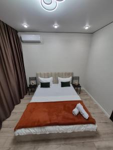 ein Schlafzimmer mit einem großen Bett mit einer braunen Decke in der Unterkunft Love & Happiness in Almaty