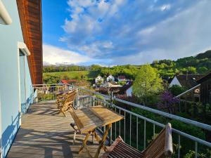 a wooden deck with a wooden table and chairs on it at Das blaue Haus in Pleisweiler-Oberhofen