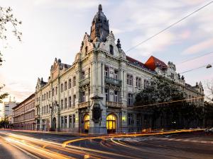 ein altes Gebäude in einer Stadtstraße mit Autos in der Unterkunft Tisza Terrace Apartman by Mital in Szeged