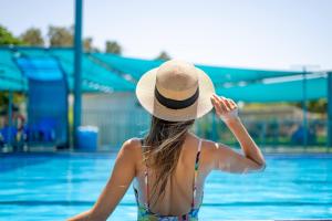 a woman in a hat sitting in a swimming pool at Etnachta Kibbutz Afik in Afik