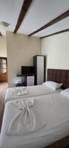 a bedroom with two white beds and a television at Kaya by Keshtjella in Durrës