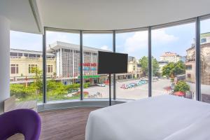 um quarto com uma janela grande com uma cama e uma tv em Tru by Hilton Hanoi Station em Hanói