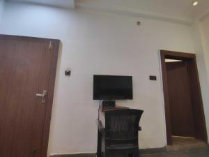 ein Zimmer mit Fernseher, Stuhl und Tür in der Unterkunft Hotel O Karond Square Bus Terminal Bhopal Formerly Hotel Munmun in Bhopal
