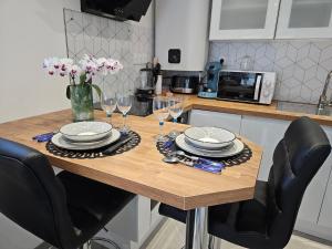 a table with plates and wine glasses on it in a kitchen at O Cottage E Lavisse in Le Nouvion-en-Thiérache