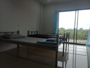 deux lits dans une chambre avec une grande fenêtre dans l'établissement มังกรเลโฮลเทลกระบี่ Mangkonlay Hostel Krabi, à Ban Khlong Chi Lat