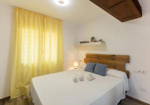 Un dormitorio con una gran cama blanca con almohadas azules. en Apartamentos Al Andalusí, en Denia