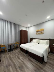 a hotel room with two beds and a table at Silana Riverfront Danang in Da Nang