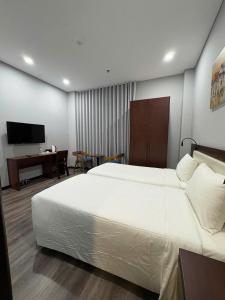 a bedroom with a large white bed and a desk at Silana Riverfront Danang in Da Nang
