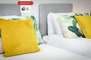 a white bed with yellow and green pillows on it at Jungle King Suite with Parking in Bedford +8 photos