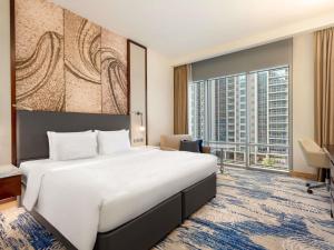 a hotel room with a large bed and a large window at Novotel Dubai Gold District in Dubai