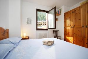 a bedroom with a large white bed with a window at WI-RO Mavignola - Trekking & Ski in Madonna di Campiglio