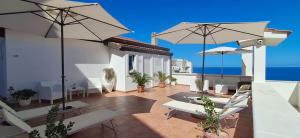 een patio met stoelen en parasols en de oceaan bij Blumarine Suite in Peschici