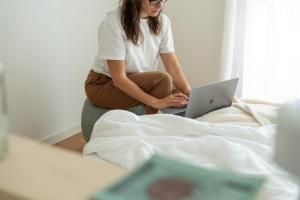 uma mulher sentada numa cama com um portátil em BrezadouraHouse, a due passi dal mare e dal centro em Rimini