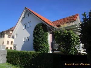 a white house with a red roof and some bushes at Ferienwohnung Stine in Stetten