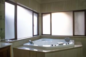 a bath tub in a bathroom with three windows at Keleo Safari Lodge in Bela-Bela