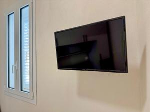 a flat screen tv on a wall next to a window at Da Nonna Concetta - 5 minutes walk from the beach in Donnalucata