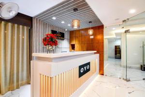 a lobby with a counter with a vase of red flowers at Hotel O The Crown in Kolkata