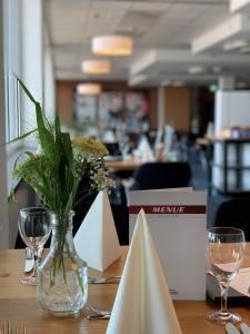 a table with a vase of flowers and wine glasses at Hotel Motodrom in Hockenheim +21 photos