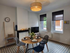 Camblain-ChâtelainにあるAu fil du temps, Meublé Tourisme 3 étoiles, Confort, Calme, Centreのリビングルーム(テーブル、椅子、時計付)