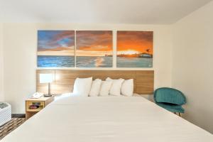 a bedroom with a bed with four paintings on the wall at Hotel Carolina - Standard King Room in Hilton Head Island